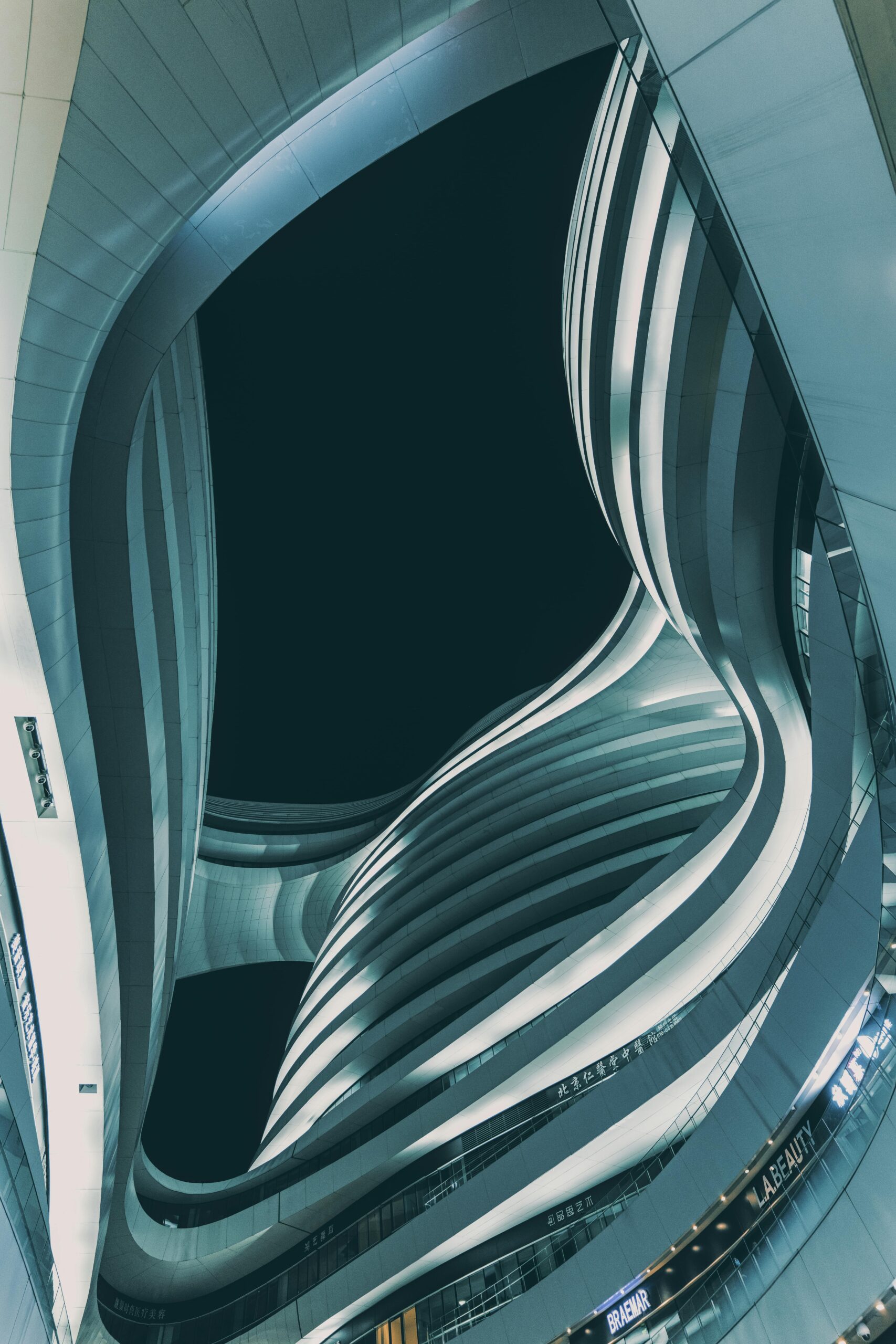 Low angle view of modern Milky Way Soho in Beijing at dusk. Futuristic curves and lines in dramatic urban setting.